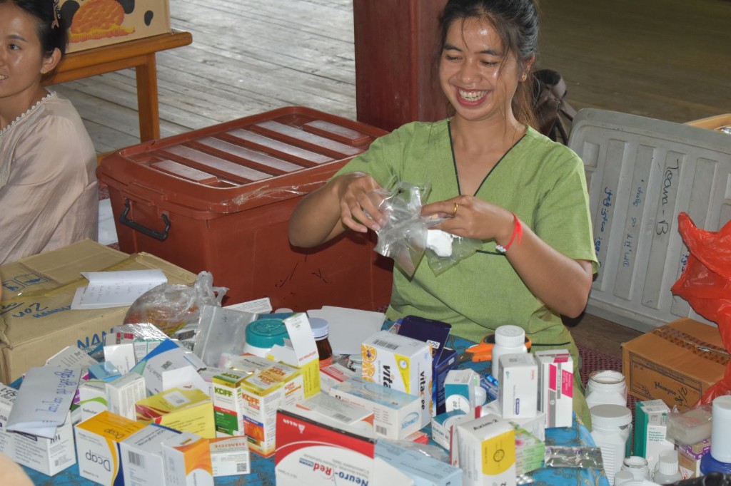 A volunteer sorting boxes of medicine at a community clinic table